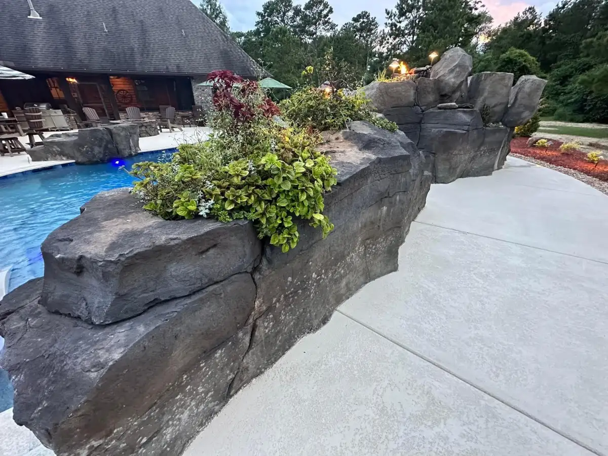 Hand-sculpted multi-tier pool waterfall with cascading water over faux rock boulders