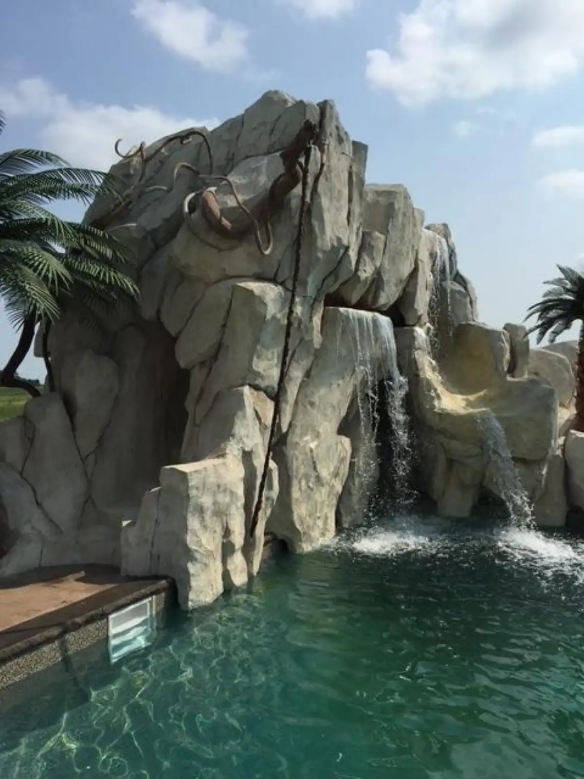 Custom hand-sculpted pool waterfall with cascading tiers and natural rock texture