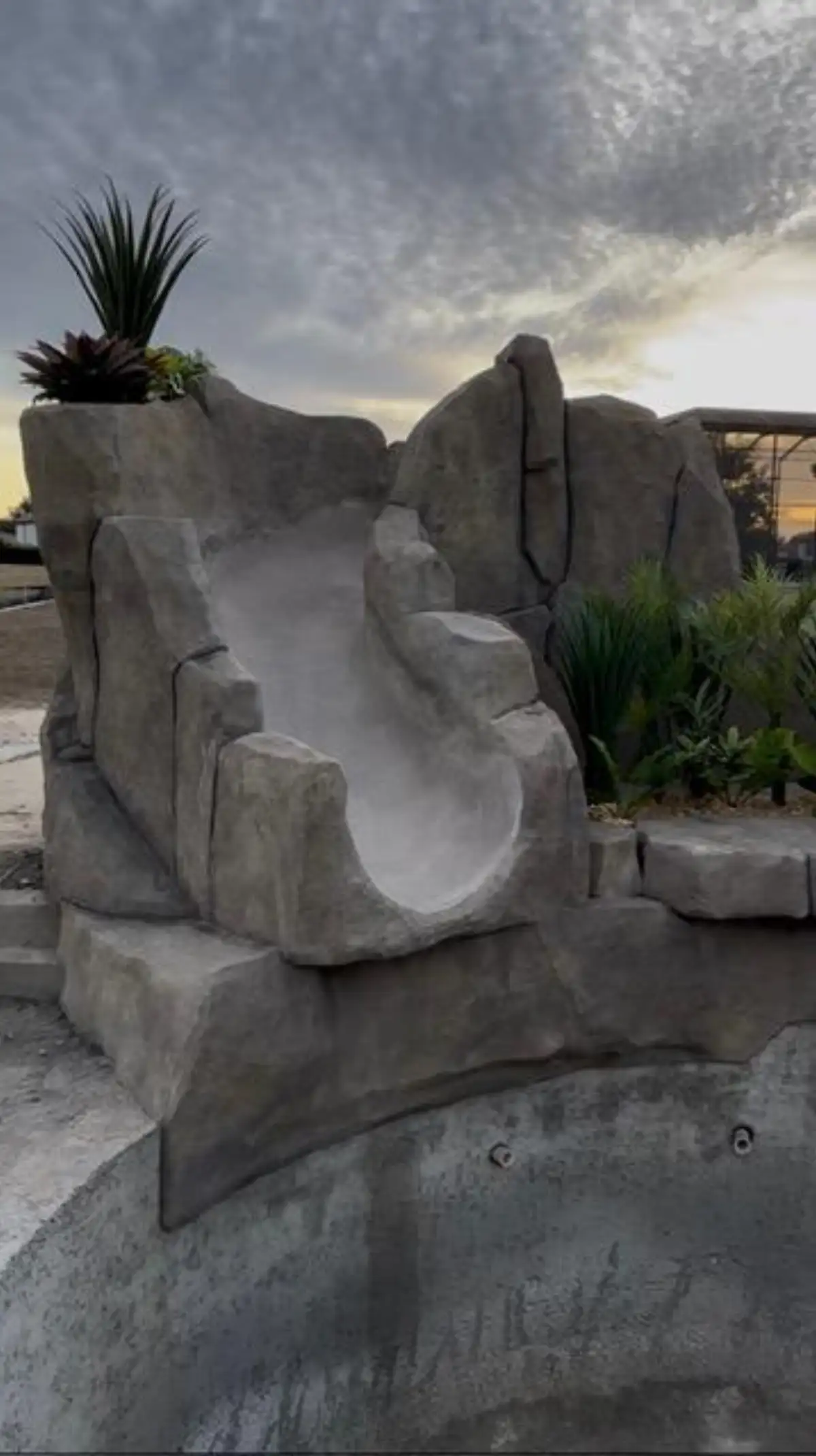 Pool slide entry point with hand-sculpted boulder surround