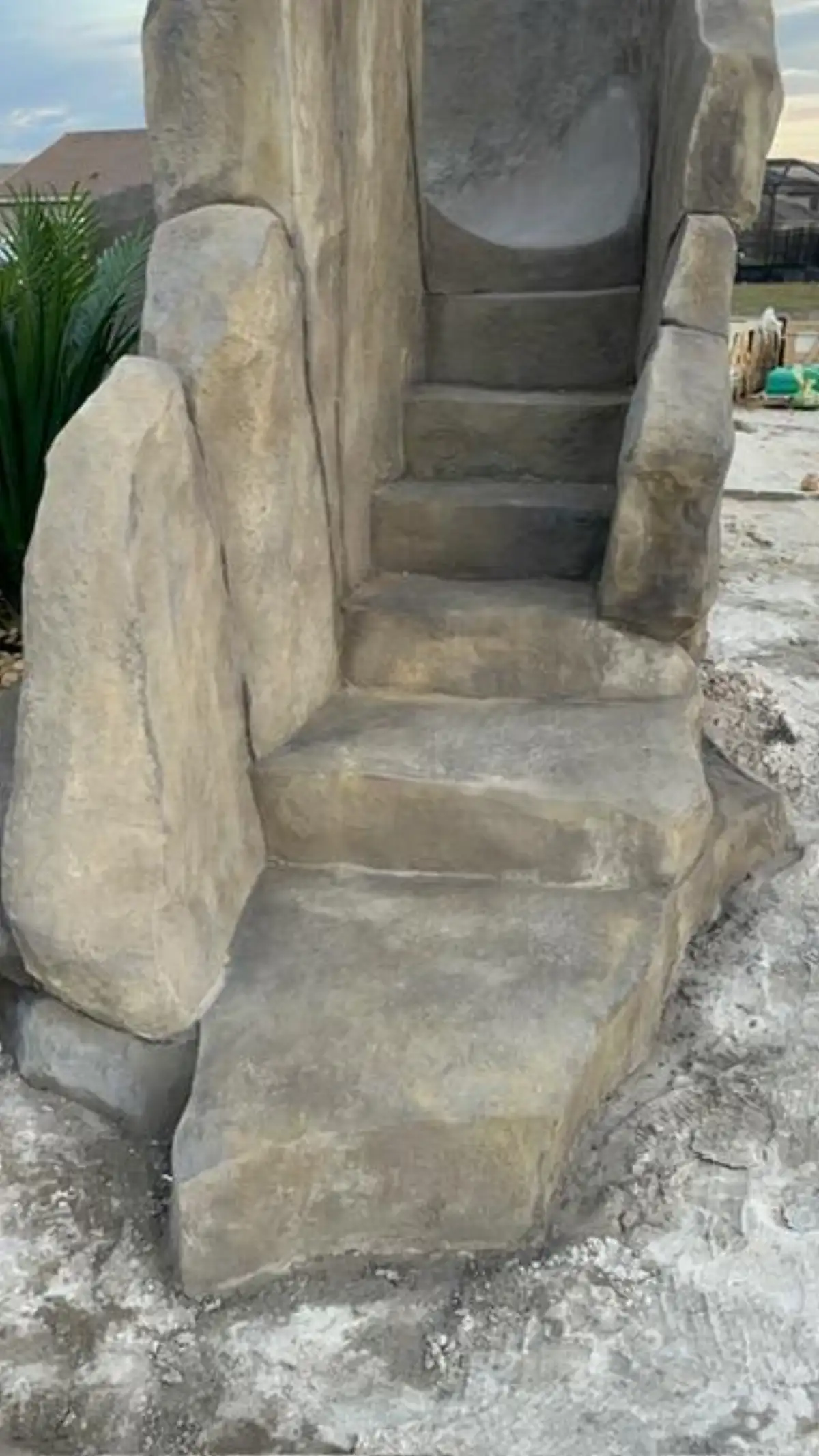 Polished concrete pool slide integrated into faux rock waterfall with smooth ride surface