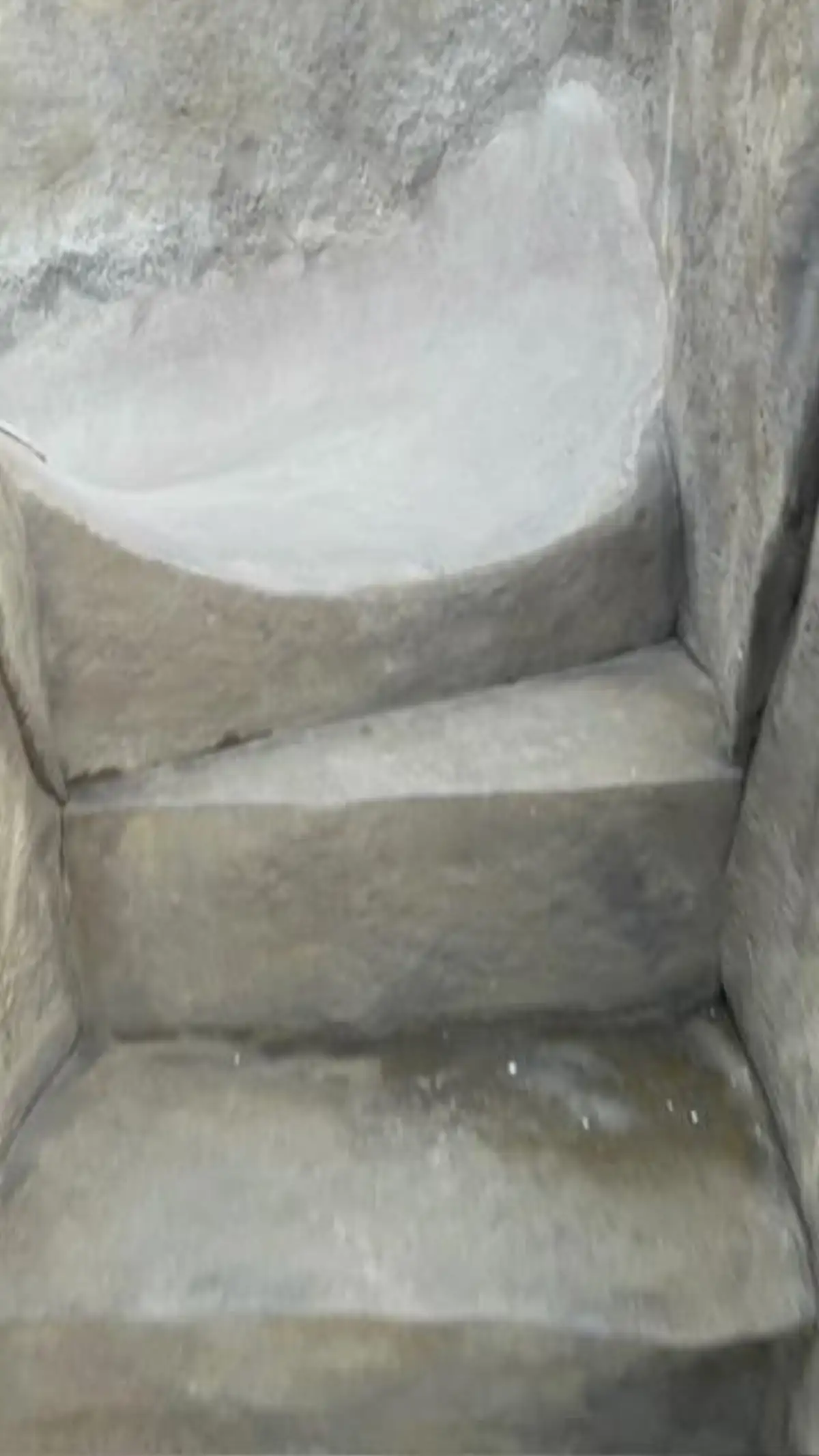 Polished concrete pool slide with water flowing into swimming pool